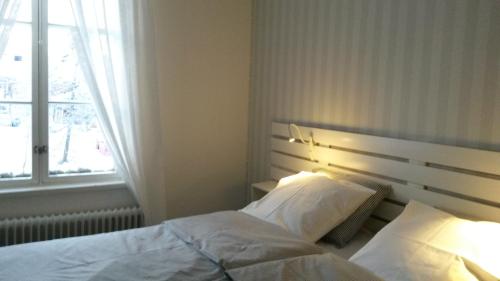 een slaapkamer met een bed met witte lakens en een raam bij Kyykerin Kartano in Outokumpu