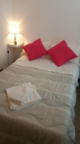a bed with two red pillows on top of it at Garden Suite in Genova