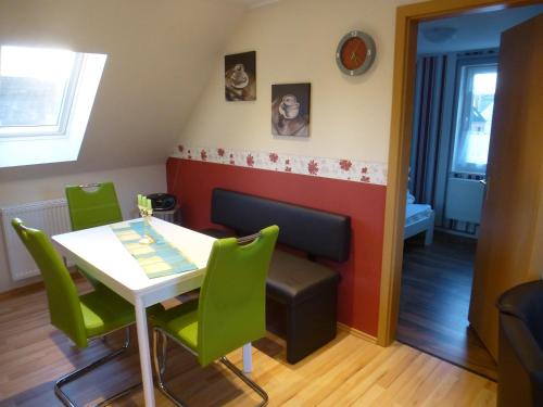 een eetkamer met een tafel en groene stoelen bij As bi uns to Huus in Wilhelmshaven