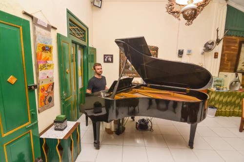 a man standing next to a piano in a room at Pendopo Andari Homestay in Yogyakarta