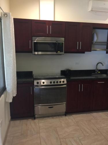 a kitchen with a stove and a microwave at Guest House in Playa Flamingo