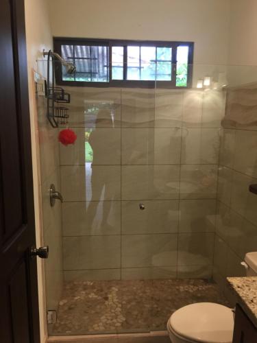 a bathroom with a glass shower with a toilet at Guest House in Playa Flamingo