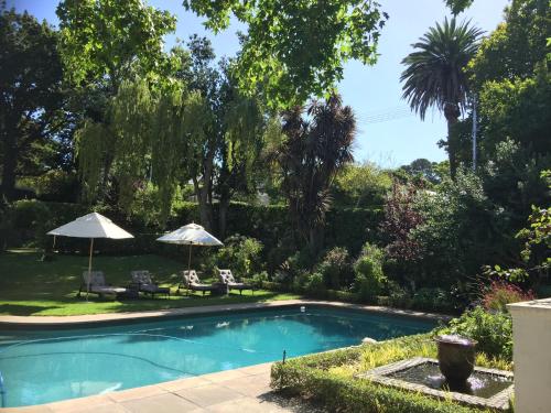 a swimming pool in a yard with two umbrellas at Chambery in Cape Town