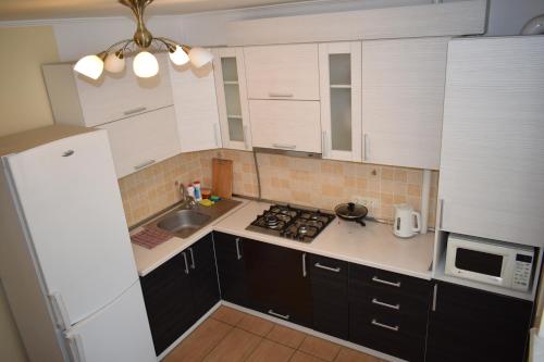 una pequeña cocina con armarios blancos y fregadero en Apartment on Demyanchuka 1A en Rivne