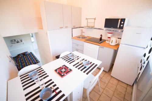 a kitchen with white cabinets and a white table and chairs at Appartements Les Déferlantes Mimizan-plage in Mimizan-Plage