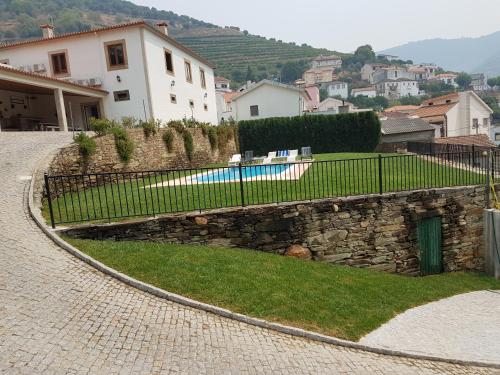 a stone wall with a fence in front of a house at Casa grande Covelinhas in Covelinhas