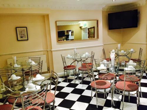 comedor con mesas y sillas y TV en Classic Hyde Park Hotel, en Londres