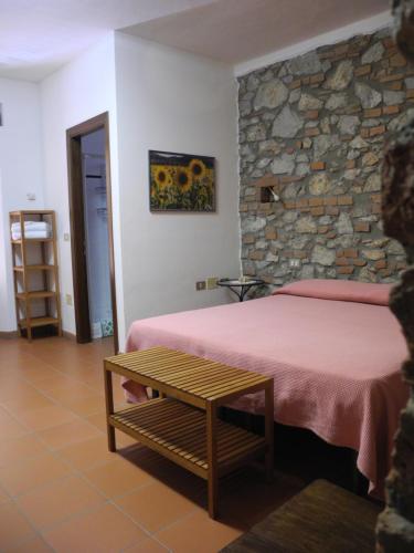 a bedroom with a bed and a stone wall at PODERE OSLAVIA AZ.AGR.BIO GIANNINI in Alberese