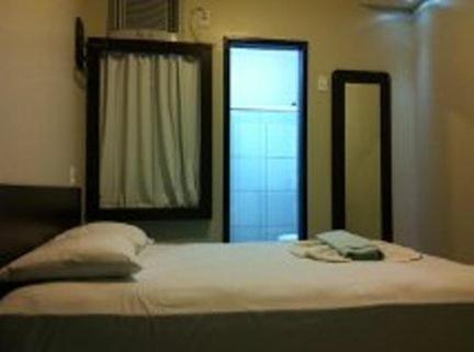 a bed with two pillows and a mirror in a room at Ferrari Palace Hotel in Boa Vista