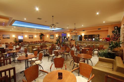 a restaurant with tables and chairs and a bar at Thea Hotel in Paralía Kímis