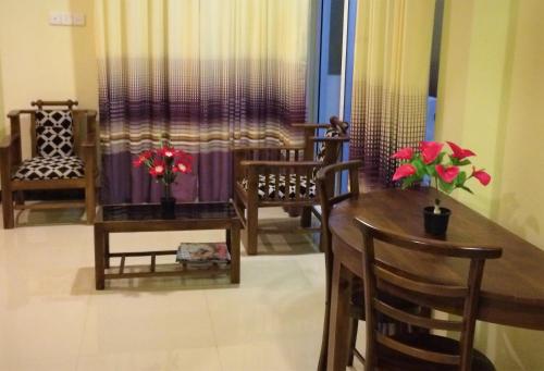 a dining room with a table and chairs and flowers at Romeo and Juliet Guest House in Negombo