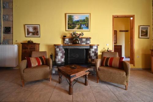 a living room with a fireplace with chairs and a table at Villa Onar a stone house with amazing view in Stoupa