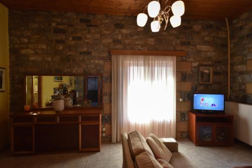 a living room with a window and a television at Villa Onar a stone house with amazing view in Stoupa