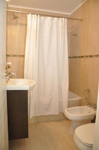 a bathroom with a white shower curtain and a toilet at Building Albar in Pinamar
