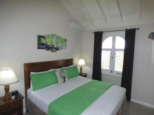 Un dormitorio con una cama con sábanas verdes y una ventana en Beach One Bedroom Suite A29, en Ocho Ríos