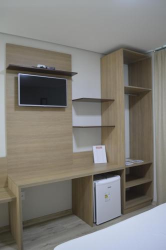 an office cubicle with a desk with a tv and shelves at Villa Rio Branco Hotel Concept in Rio Branco