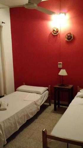 2 Betten in einem Zimmer mit roter Wand in der Unterkunft Residencial Castelar in Merlo