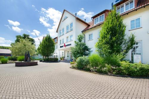 a large white building with trees and a courtyard at Hotel Montana in Guxhagen