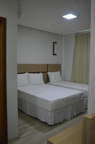 two beds in a room with white walls at Villa Rio Branco Hotel Concept in Rio Branco