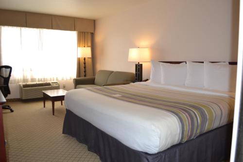 a hotel room with a large white bed and a chair at Country Inn & Suites by Radisson, Abingdon, VA in Abingdon