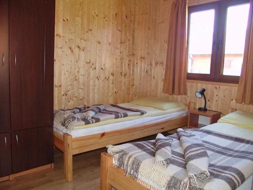 two twin beds in a room with wooden walls at Domki Letniskowe Pikamar in Darłówko