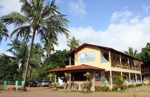 a building with a palm tree in front of it at Pousada Lua Cheia in Japaratinga