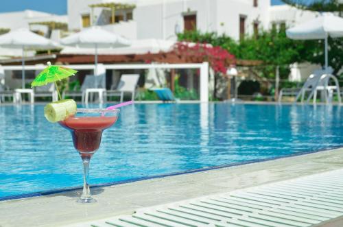 a drink sitting on a table next to a swimming pool at Birikos Hotel & Suites in Agios Prokopios