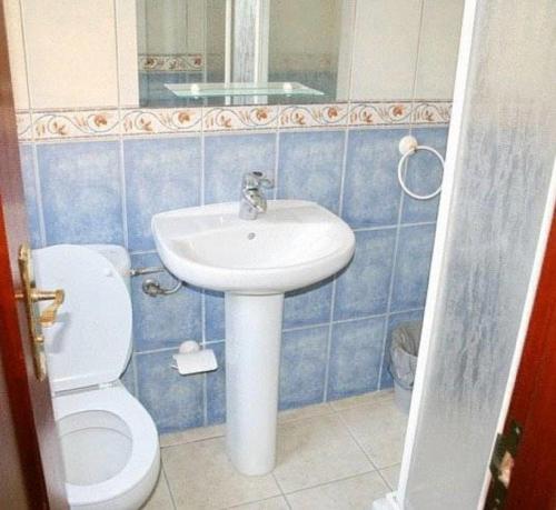 baño de azulejos azules con lavabo y aseo en La Vista Pension, en Guía de Isora