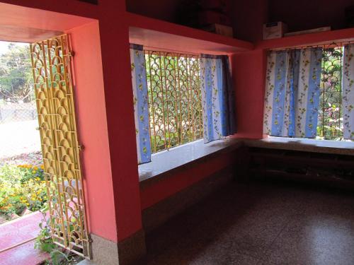 a room with three windows with blue curtains at Pubali Homestay in Bolpur