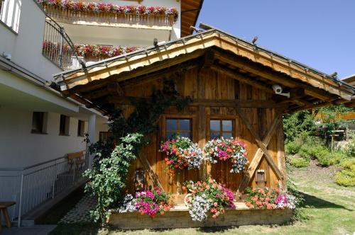 a small house with flowers on the side of a building at Hotel Scherlin in Ortisei