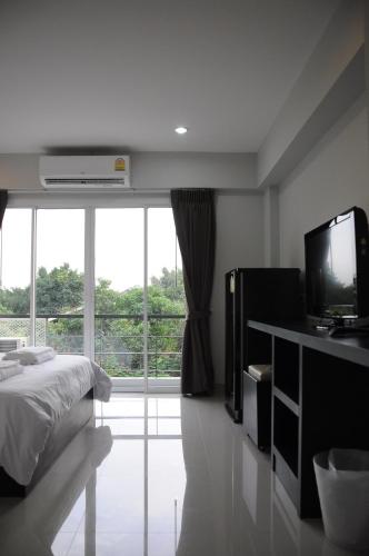 a bedroom with a bed and a tv and a window at Delight Residence in Bangkok