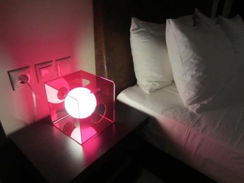 a pink alarm clock on a table next to a bed at island in Pefki