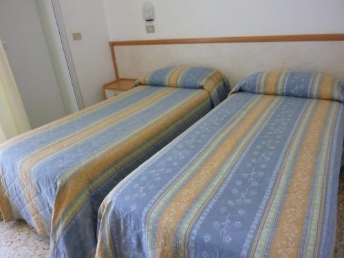 two beds sitting next to each other in a room at Hotel Apis in Rimini