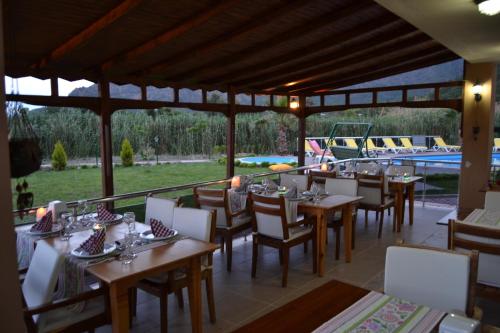 a restaurant with wooden tables and chairs and a pool at Ada Adrasan Hotel in Adrasan