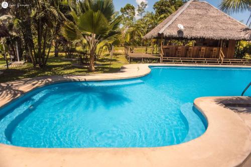 a swimming pool at a resort with a hut at Manish Hotel Ecólogico in Pucallpa