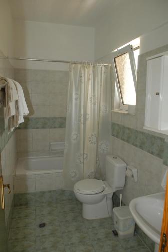 a bathroom with a toilet and a tub and a sink at Barbie Hotel Apartments in Ialyssos