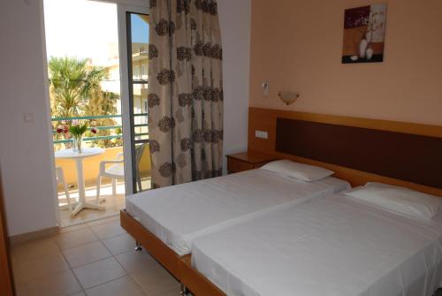 a bedroom with two beds and a balcony at Barbie Hotel Apartments in Ialyssos