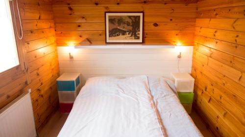 a small bedroom with a bed in a wooden room at Chaletparc Krabbenkreek in Sint Annaland