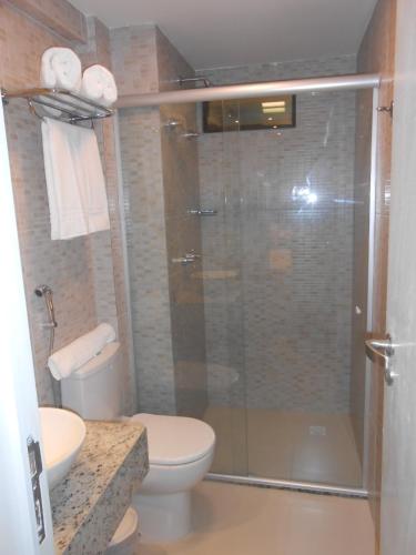 a bathroom with a toilet and a glass shower at Tabatinga Residence Apart Hotel in Jacumã