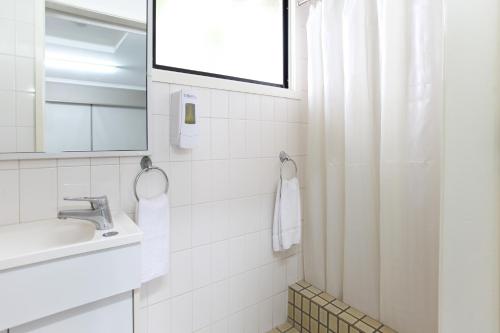 La salle de bains blanche est pourvue d'un lavabo et d'un miroir. dans l'établissement Tandara Hotel Motel, à Sarina
