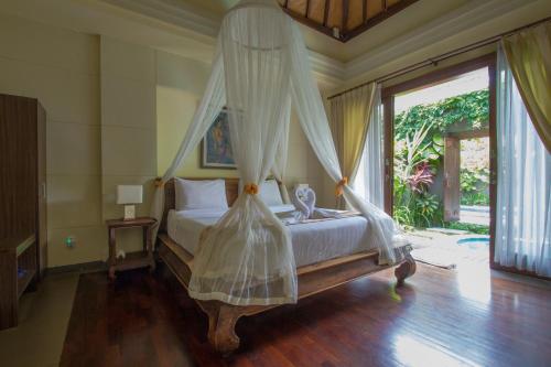 a bedroom with a bed with a mosquito net at Ladera Villa Ubud in Ubud