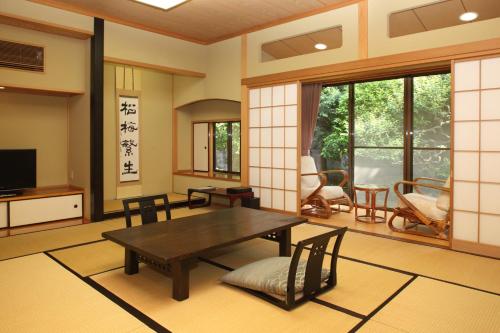 - un salon avec une table et des chaises en bois dans l'établissement Hanare Kitaoka, à Itō