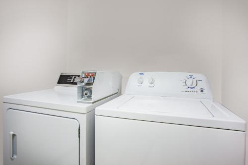 una lavadora y secadora blancas junto a una nevera en Ramada Limited 100 Mile House en One Hundred Mile House