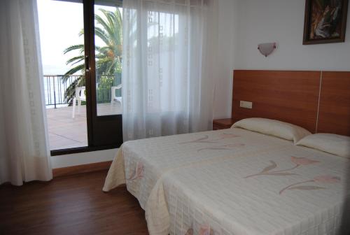 a bedroom with a bed and a balcony with a view at Hostal Carabela in Areas