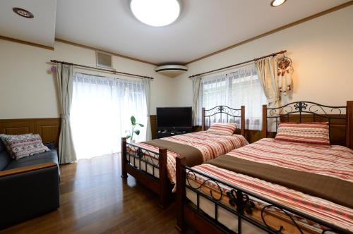 a bedroom with two beds and a tv and a window at Guesthouse Kimiko in Kasagicho