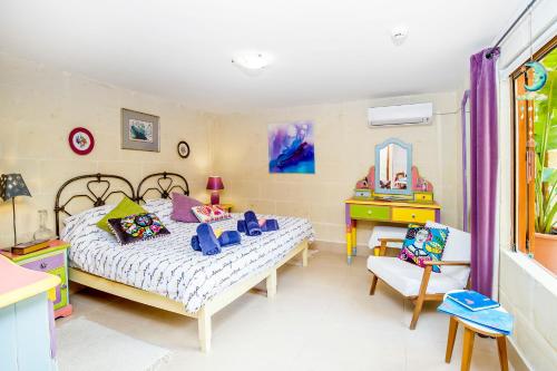 a bedroom with a bed and a table and a chair at Dar tal-Kaptan Boutique Maison in Għasri