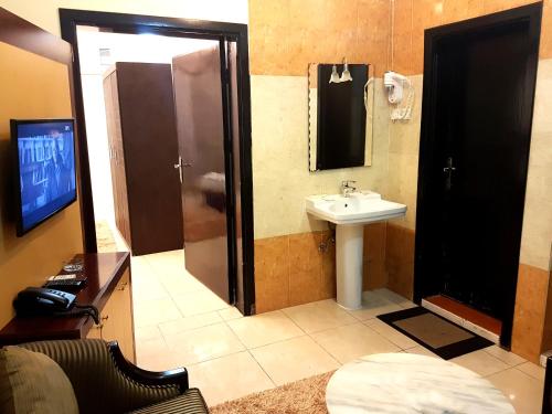 a bathroom with a sink and a shower with a mirror at Qasr Allathqiah Furnished Apartment 4 in Khamis Mushayt