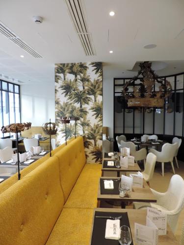 a restaurant with tables and chairs and a large mural at Hotel L'Arbre Voyageur - LILLE in Lille