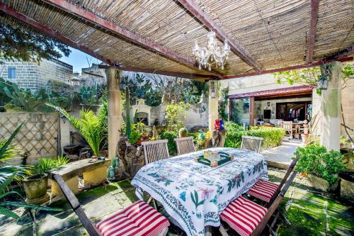 a patio with a table and chairs and a chandelier at Dar tal-Kaptan Boutique Maison in Għasri