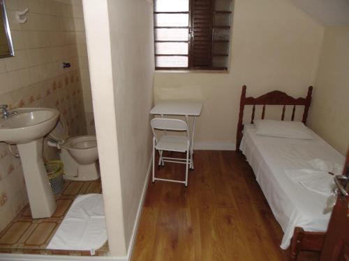 a small bathroom with a bed and a sink and a toilet at Avenida Hotel in Presidente Prudente